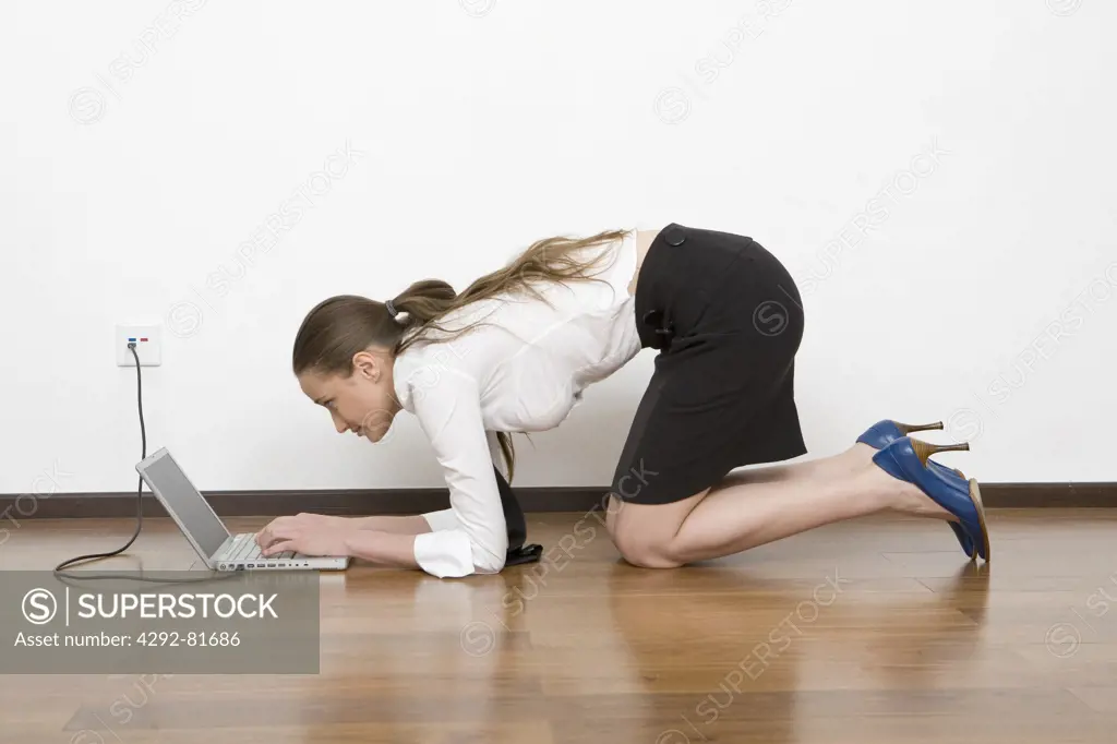 Woman kneeling on floor using laptop