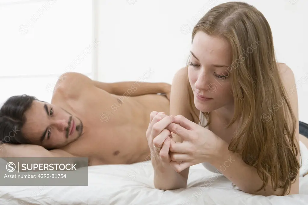 Couple lying on bed, worried man looking at
