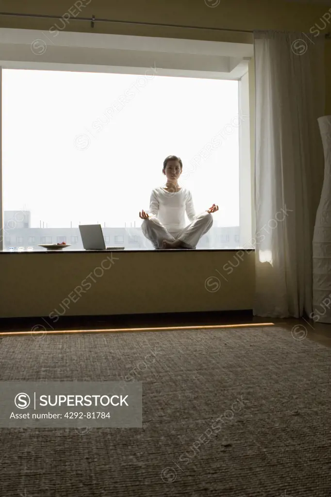 Asian woman doing yoga with laptop