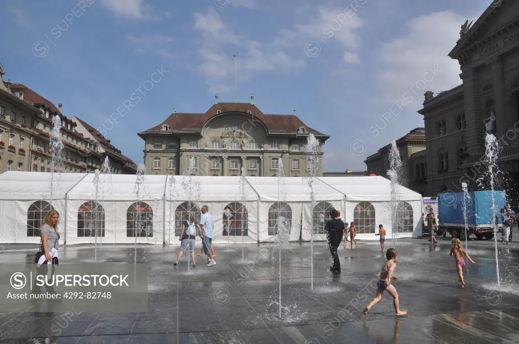 Europe, Switzerland, Berne, Parliamen Square, children playing amidst fountains.