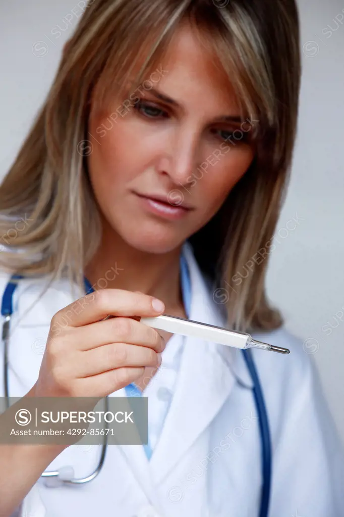Female doctor looking at thermometer