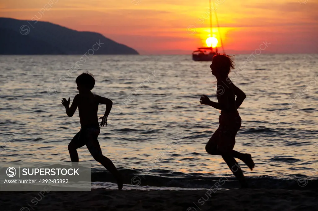 Children running on beach at sunset