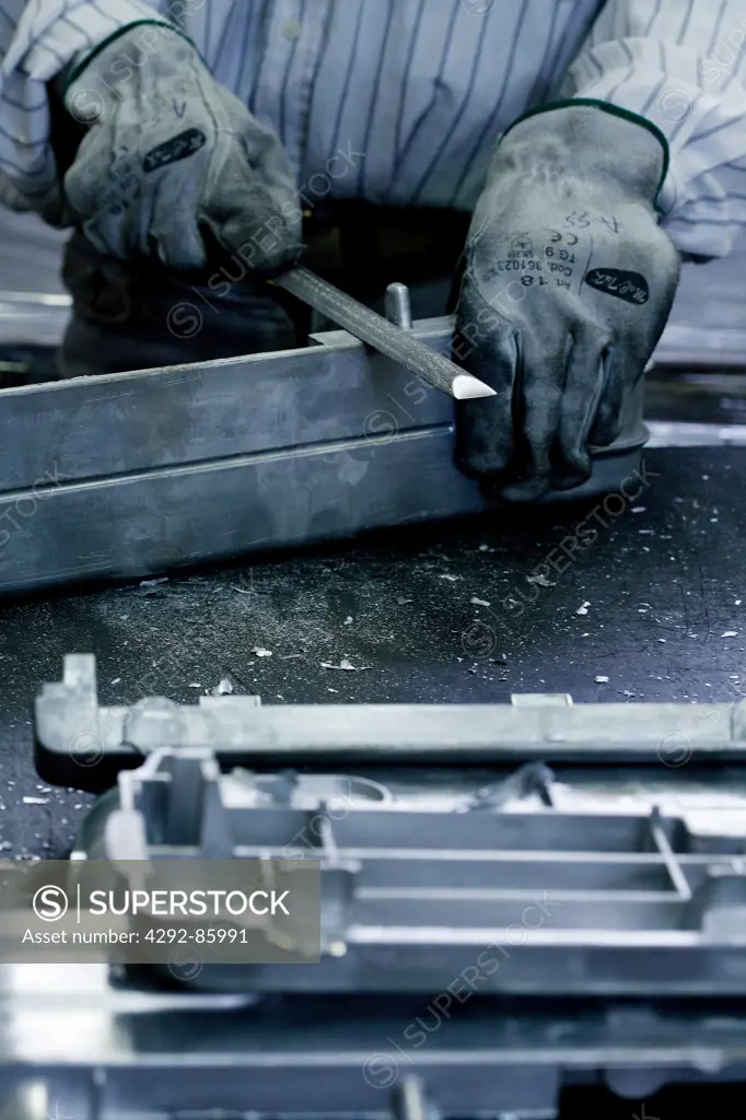 Manual worker in fabric working on aluminium bars