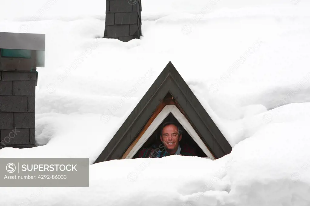 Man looking through snow covered window house