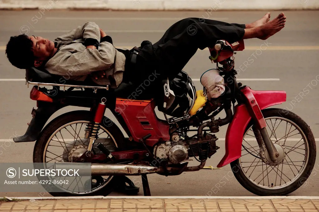 Cambodia, local man sleeping on his motorcycle