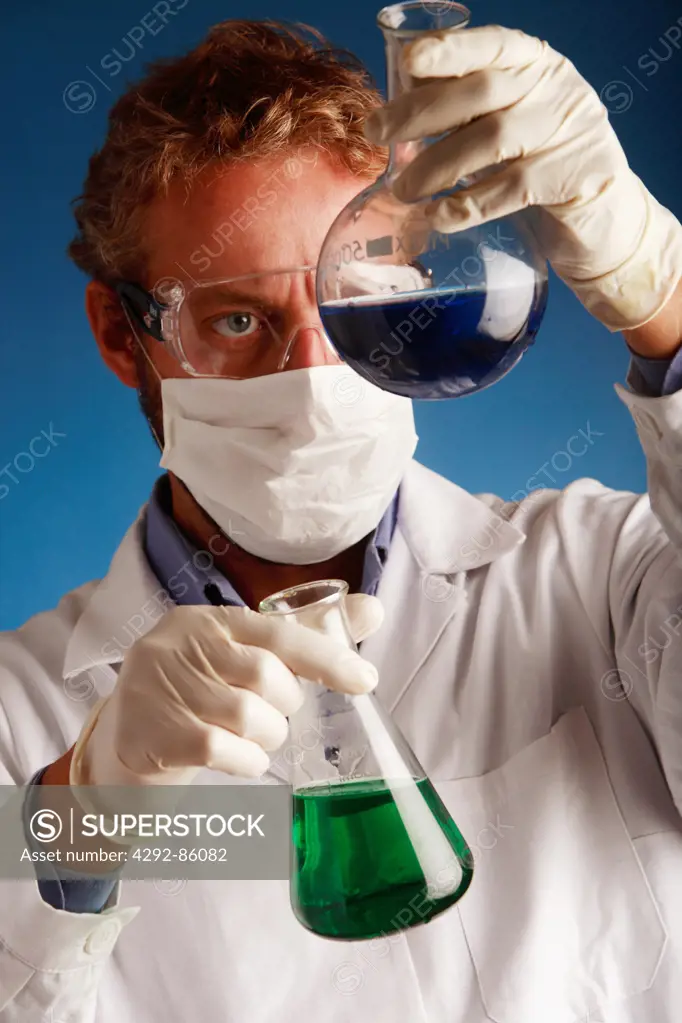 Male scientist examining flasks