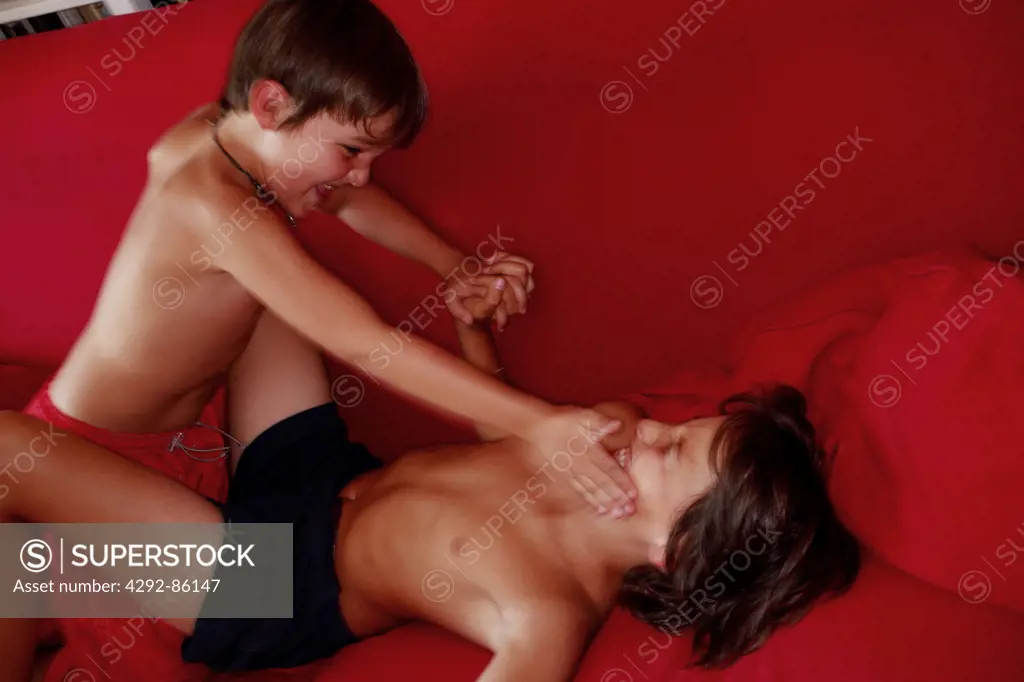 Two boys fighting on sofa