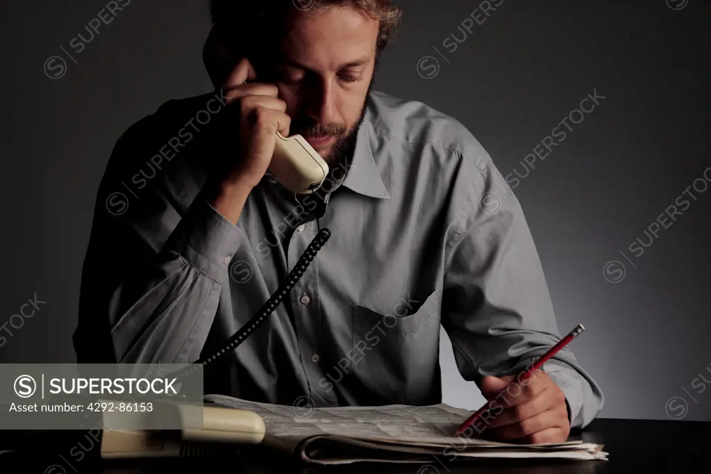 Man on telephone while reading job listing
