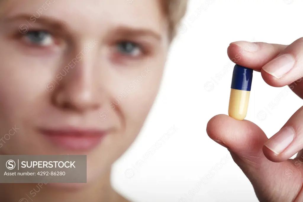 Young woman holding pill close up