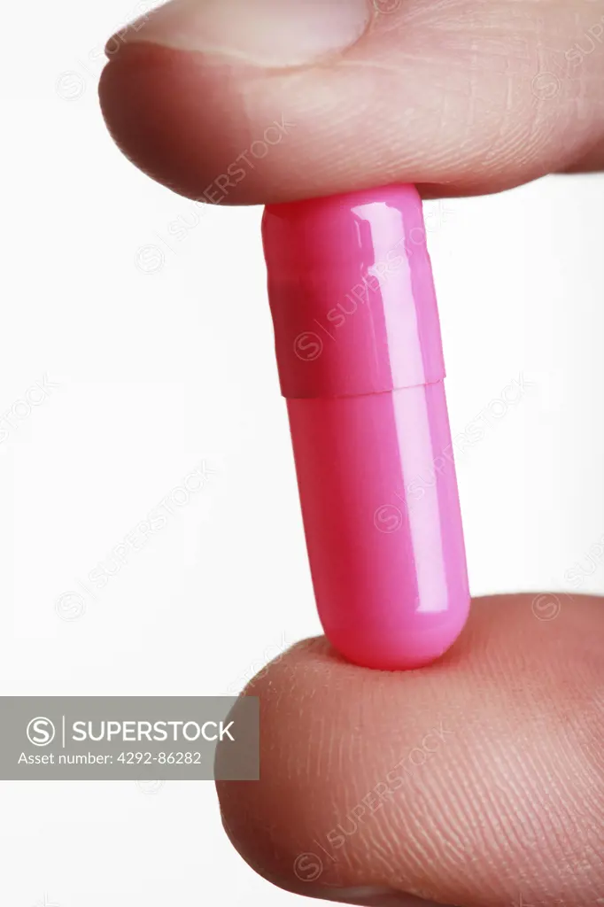 Fingers holding pill close up