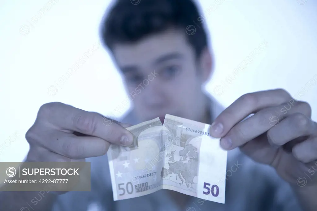 Young man tearing euro banknote