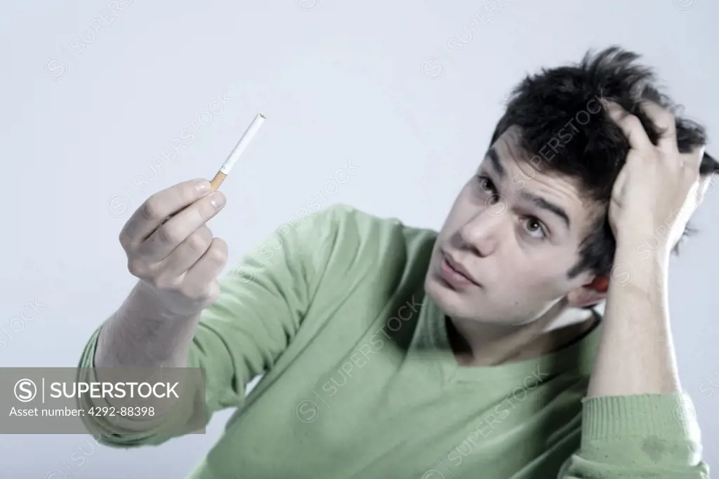 Young man looking at unlit cigarette