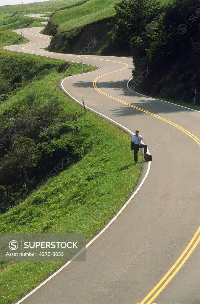 Business man walking on curving Highway 1 along California coast