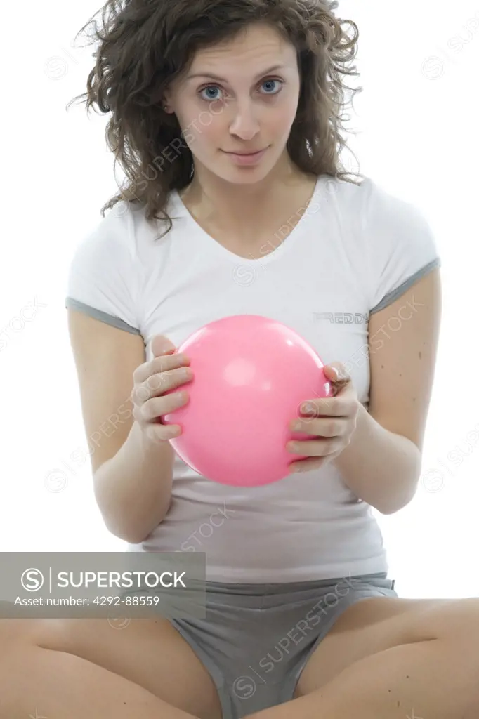 Young woman exercising with pink ball