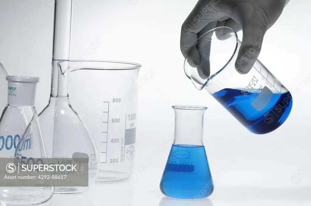 Hand of scientist pouring liquid in flask
