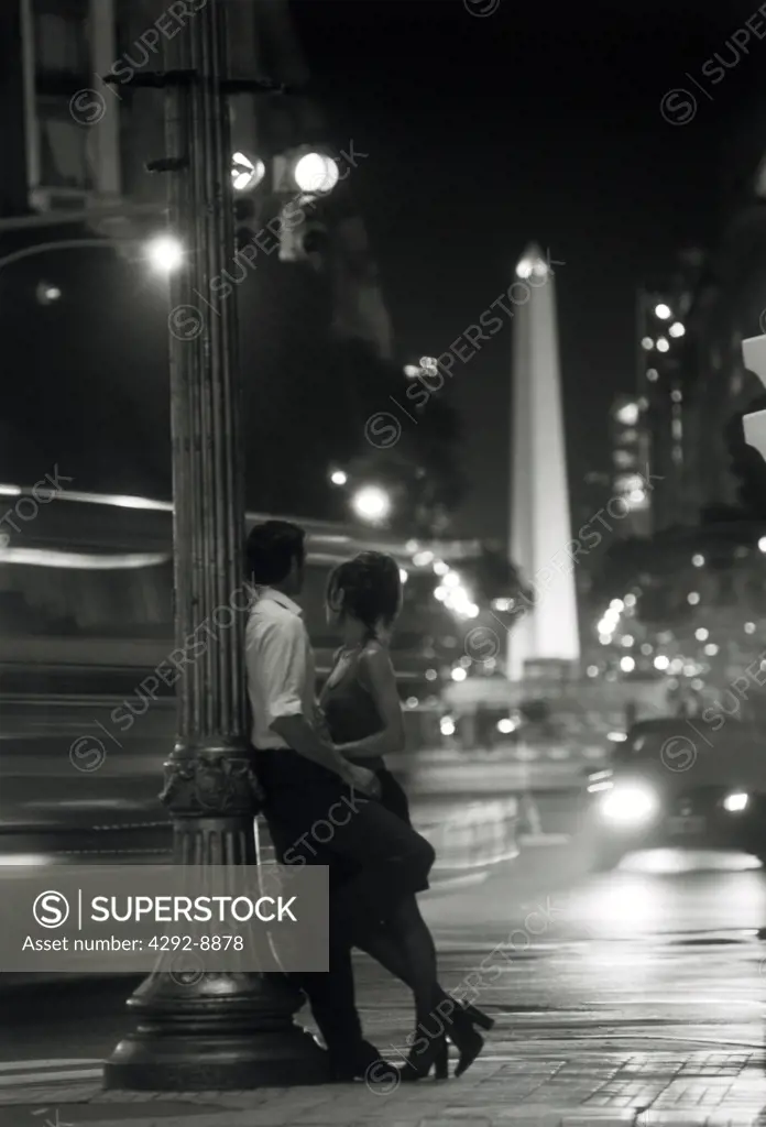 Argentina, Buenos Aires. Couple leaning against lamp post at Plaza de Mayo.