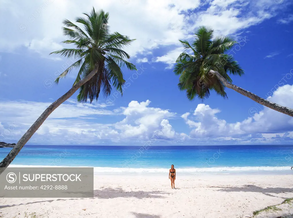 Woman walking white sandy beach at Intendence Beach on Mahe Island in Seychelles