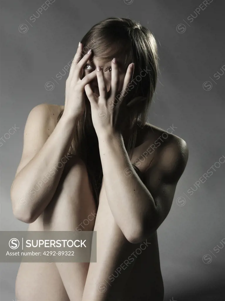 Woman covering eyes with hands, peeking through fingers