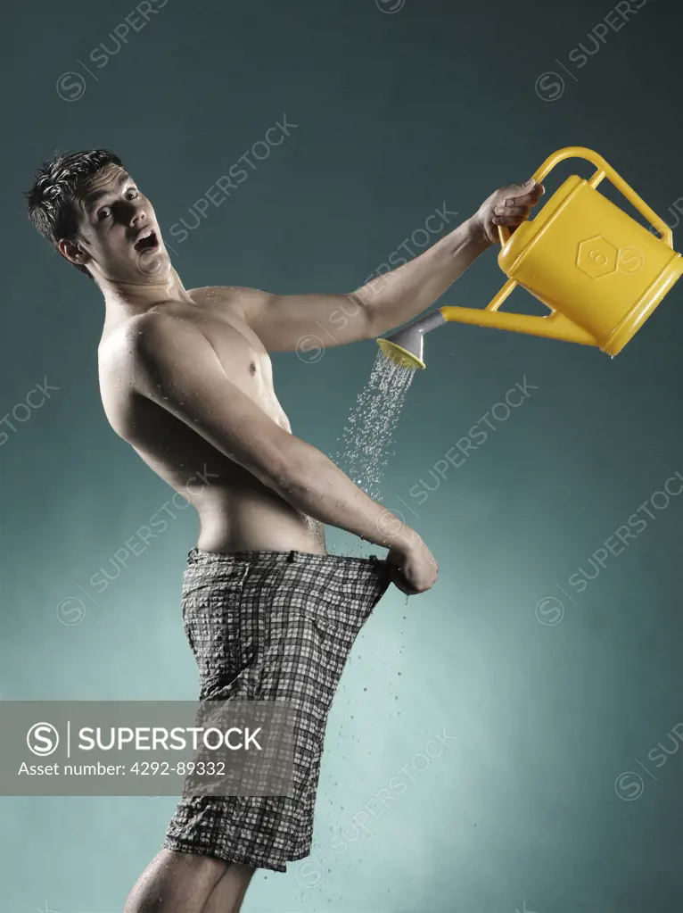Man pouring water with watering can into his trousers