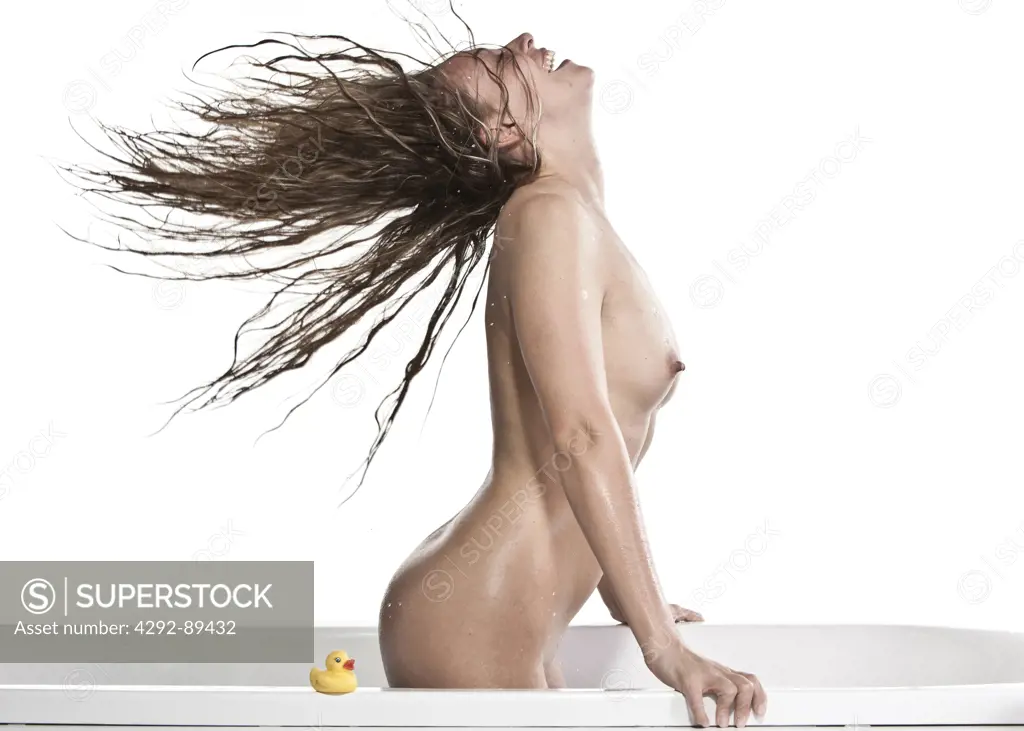 Young woman in bathtub throwing wet hair back