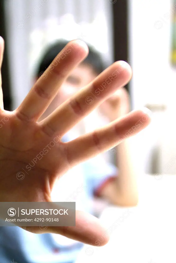 Young boy hiding behind outstretched hand