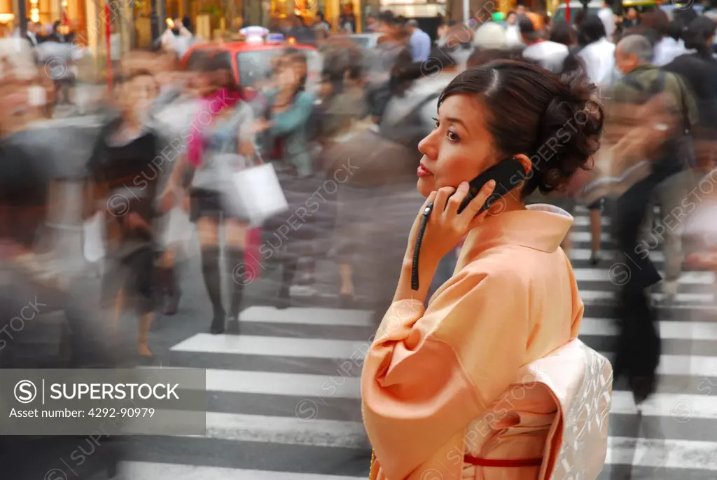 Japan, Tokyo, woman in kimono talking on mobile in the street