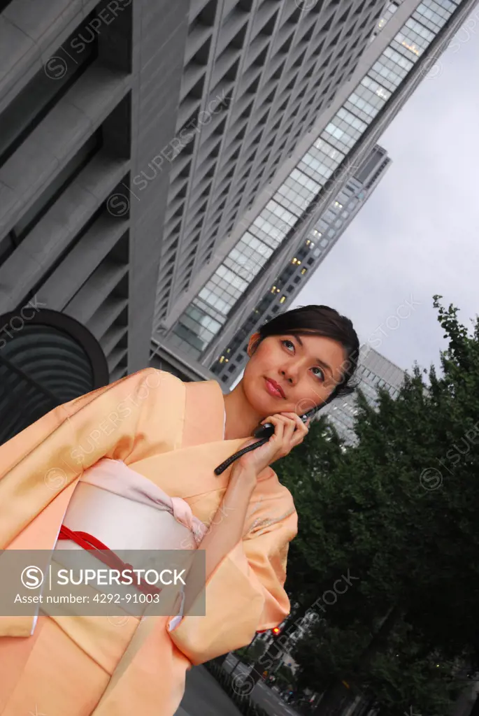 Japan, Tokyo, financial district, woman in kimono talking on mobile outdoor