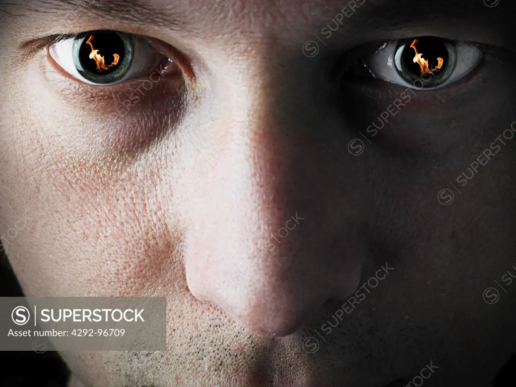 Close-up of man's eyes with flames reflected