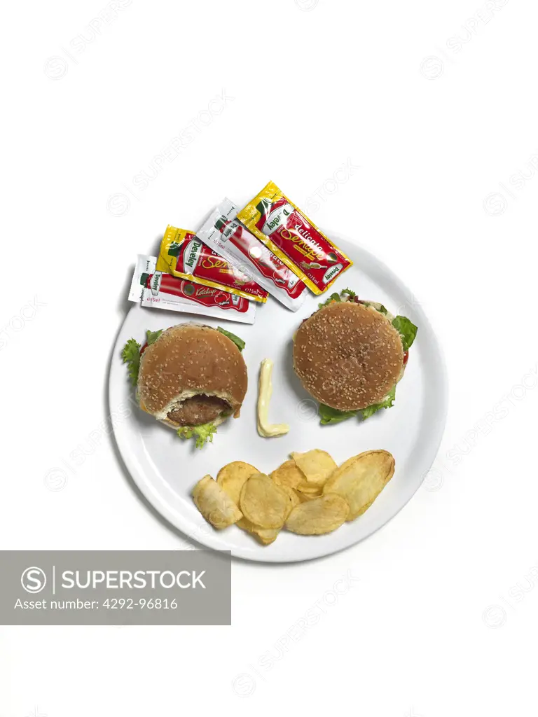 Hamburgers, potato chips and ketchup on dish shaped as human face
