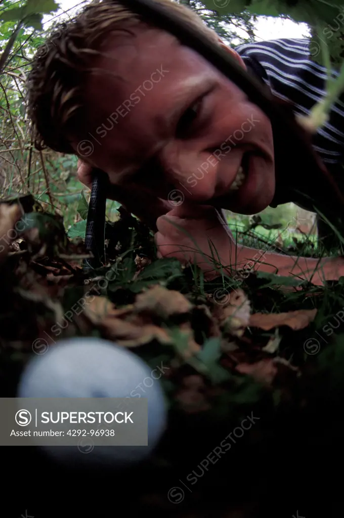 Golfer searching through grass for ball