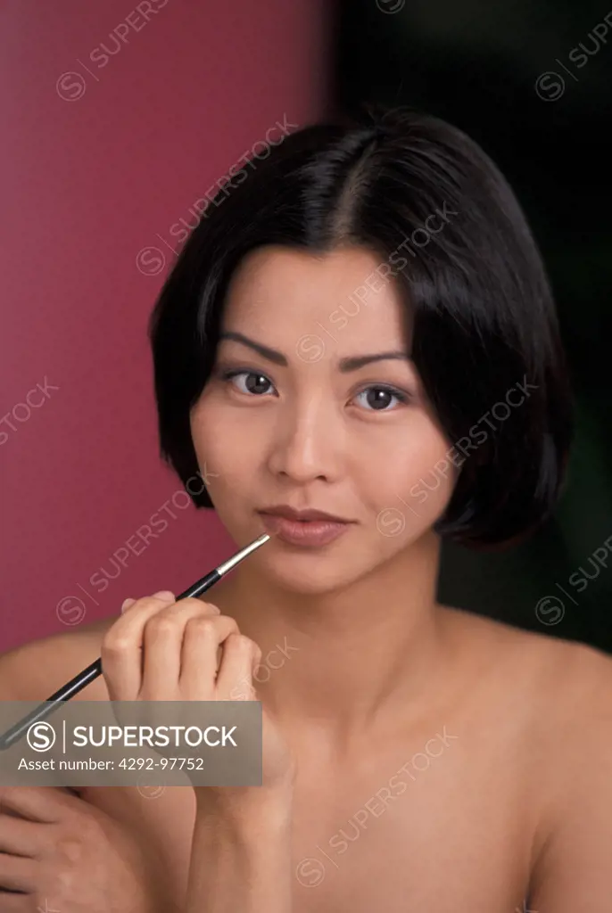 Asian woman applying lipstick