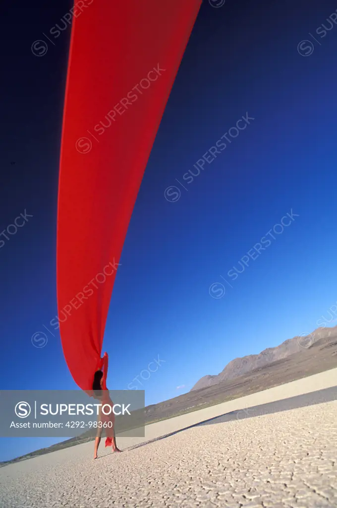 Nude on a dry lake bed with red fabric