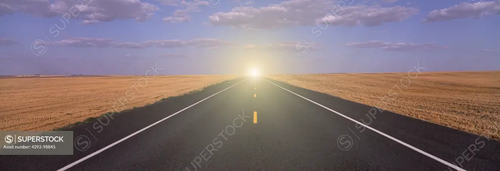 USA, eastern Washington, country road through wheath fields, bright light on horizon