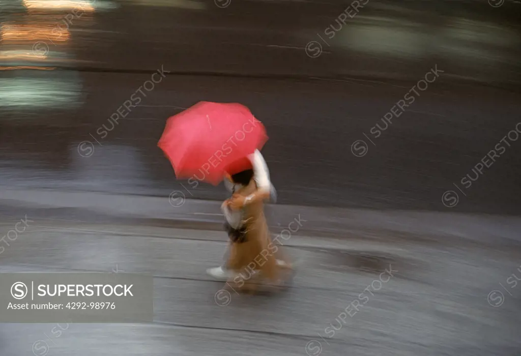 Japan, Tokyo, man and woman walking quickly with umbrella