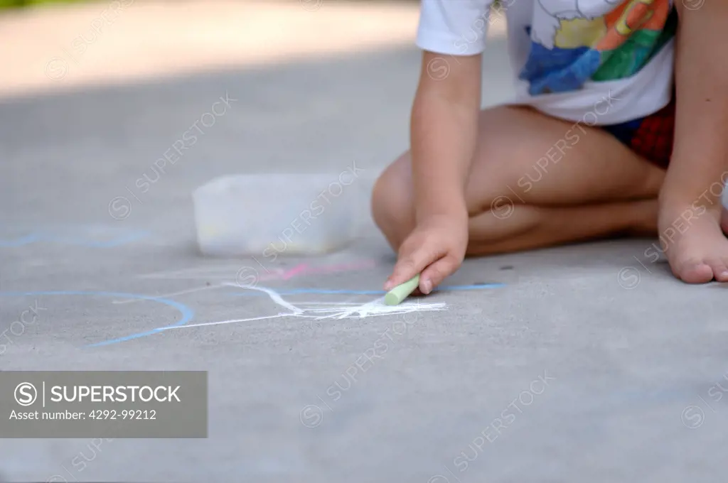 Boy drawing on pavement with chalk
