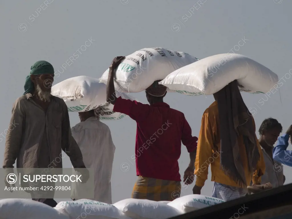 Bangladesh,Dhaka. Workers unloading sacks of fertilizer from boat