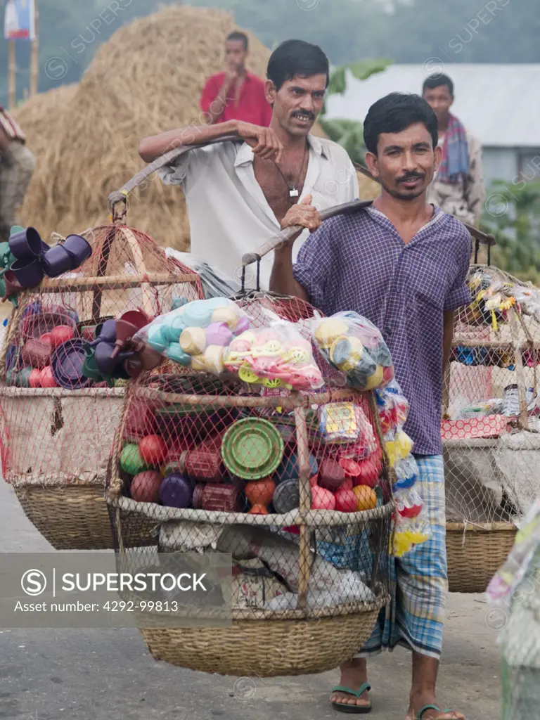 Men carrying plastic goods to sell on the street in Panishwar, Bangladesh.