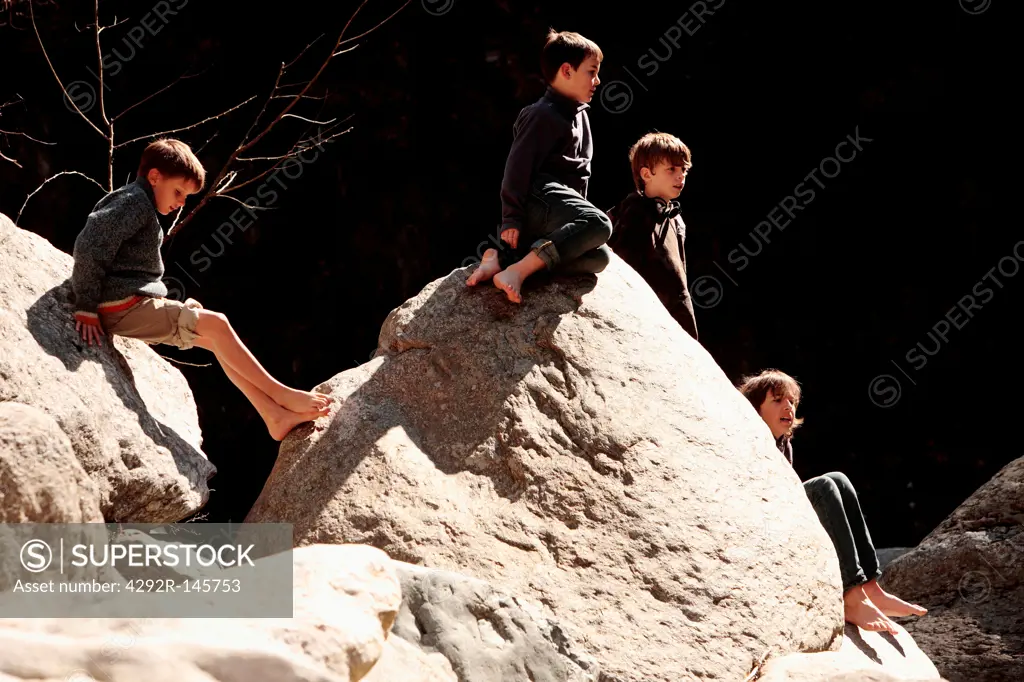 Group of friends sitting on stream rock