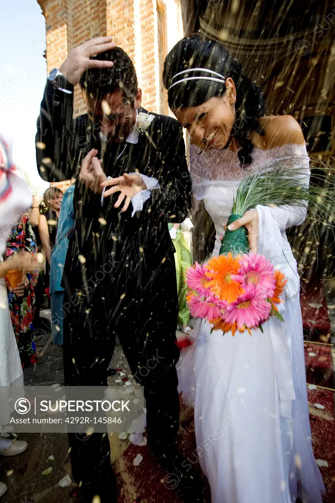 Bride and groom leaving church and guests throwing them rice