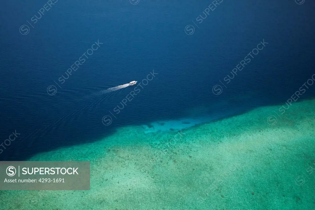 Aerial view of a tourist boat travelling next to a coral reef, Baa Atoll, Maldives.