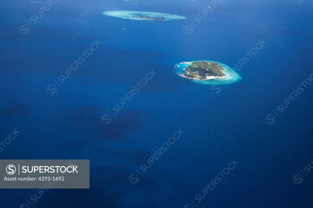 Aerial view of a small island in North Male Atoll, Maldives, with Thilafushi island in the background.