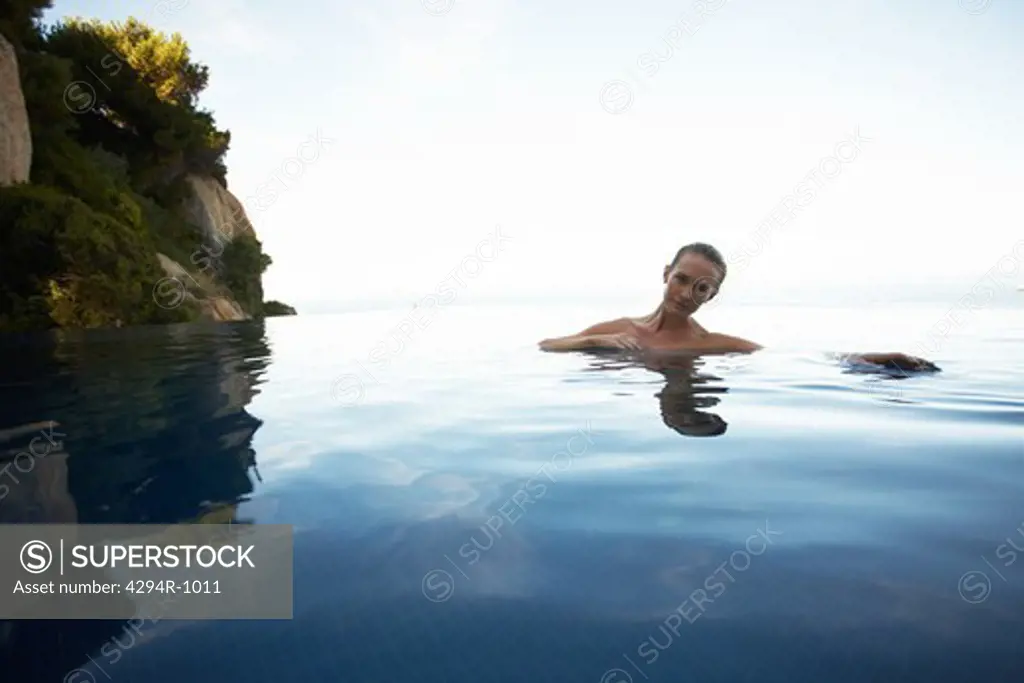 Young woman swimming in infinity pool