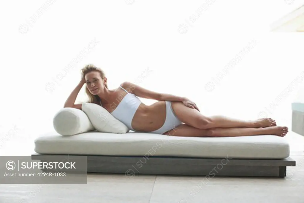 Young woman in bathing suit relaxing on futon