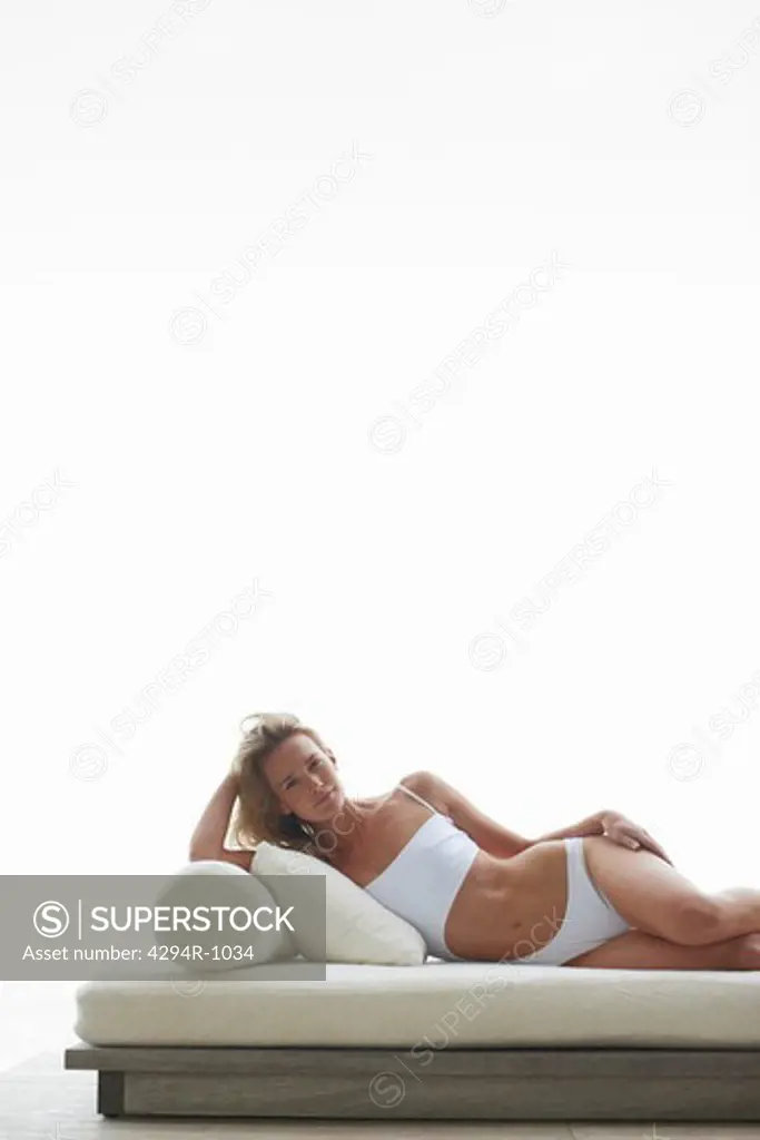 Young woman in bathing suit relaxing on futon