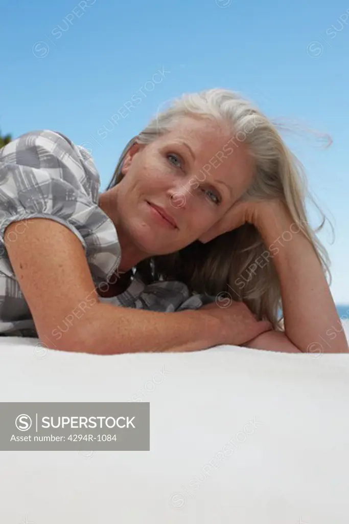 Mature woman lying outdoors with head in hand