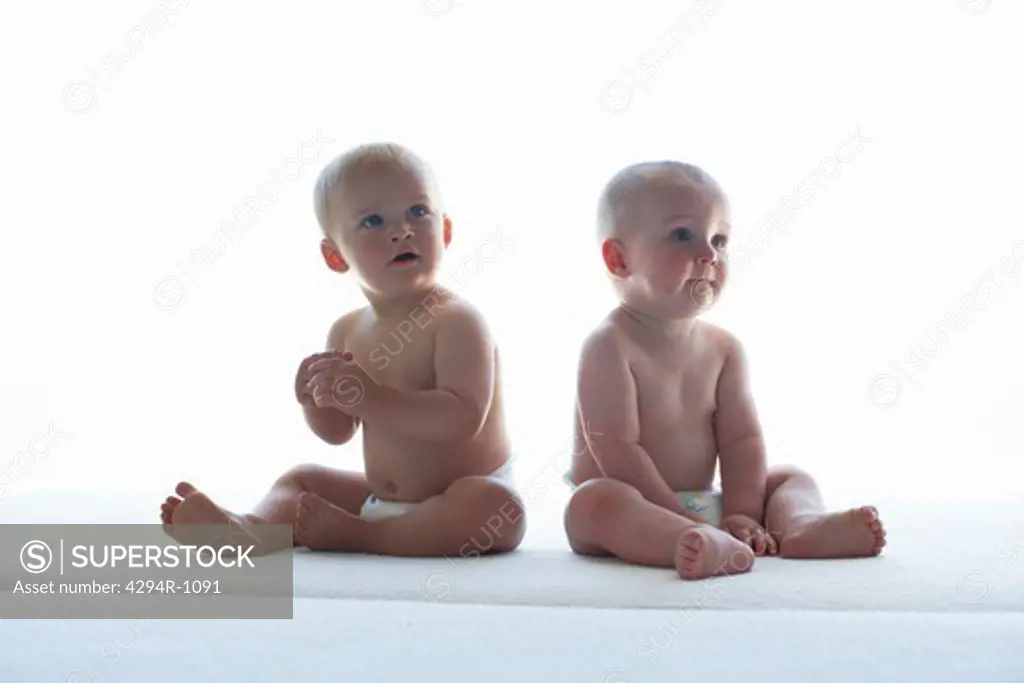 Two baby boys sitting in diapers