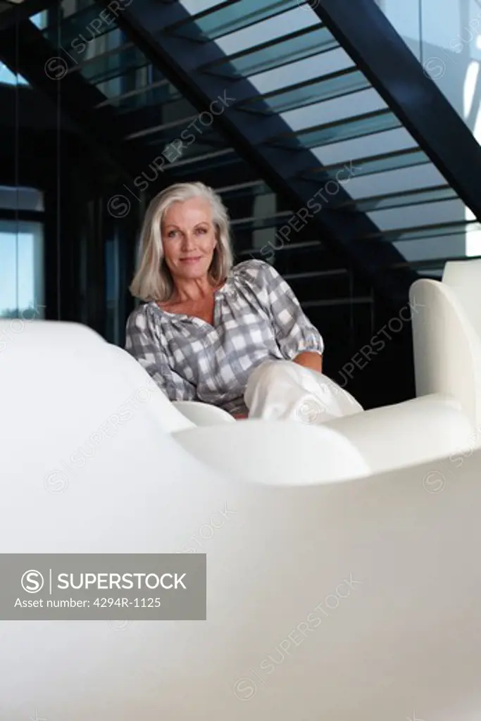 Smiling mature woman sitting in modern living room