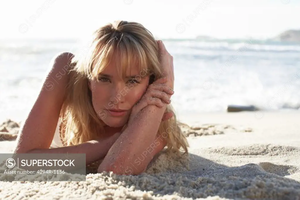 Blond young woman lying on beach