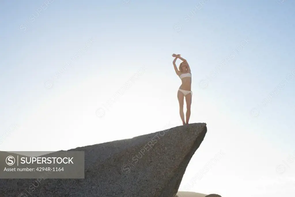 Young woman standing on rock under blue sky