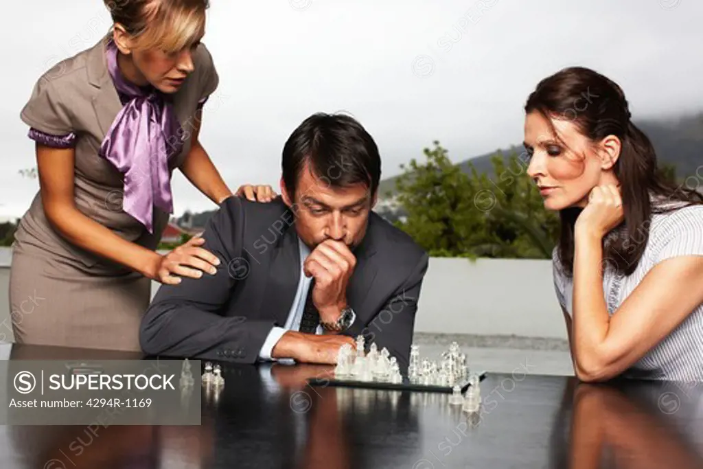 Businessman with two women sitting with chessboard